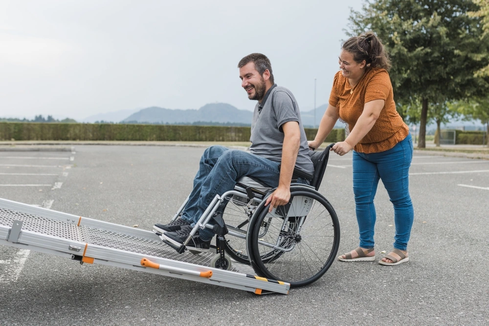 women pushing a disabled men on wheelchair up on a van